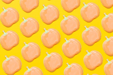 Sweet homemade pumpkin cookie with icing on yellow background pattern flat lay composition.