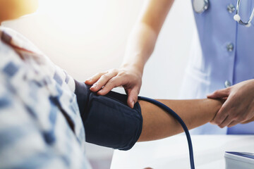 A young nurse is measuring the pressure of a patient who is admitted to the hospital.