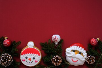 Christmas and New Years  holiday. santa claus and snowman christmas gingerbread cookies with fir branches and cones, christmas balls on a burgundy background.Sweets for the winter holidays. 