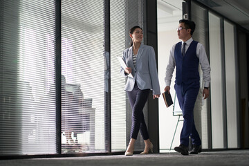 asian business man and woman walking talking in modern office