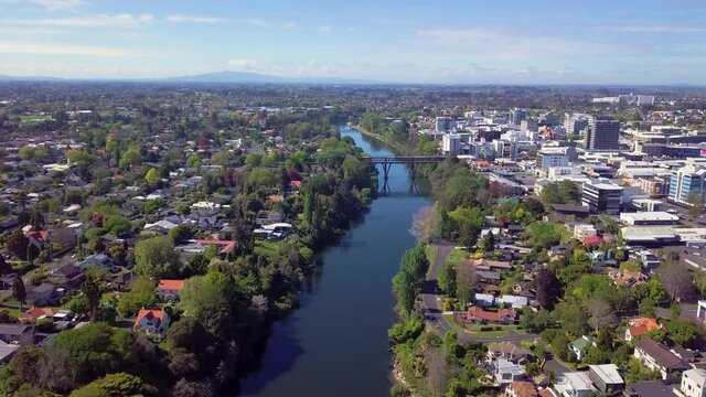 Aerial drone footage following the Waikato River through the CBD over Hamilton City in the Waikato region of New Zealand (Aotearoa)