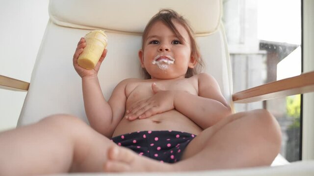 Child toddler girl with ice cream at home. Tasty yummy sweet food. Funny face