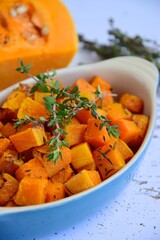 Roasted pumpkin cubes with thyme on white background