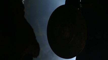 a man in ancient armor lowers a shield through the rays of light, in a black cave