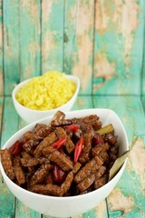 Tempeh chili soy sauce with turmeric rice. Indonesian food. Green wooden background
