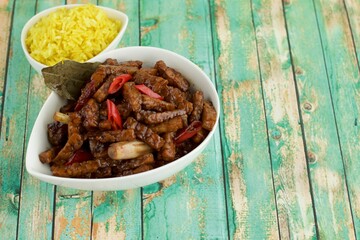 Tempeh chili soy sauce with turmeric rice. Indonesian food. Green wooden background
