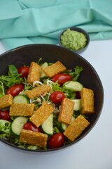 Lettuce salad with cucumber, tomato, mung bean sprouts, fried tempeh and avocado pesto sauce
