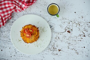 Hash browns or potato pancakes or Swiss Rösti garnish with cherry tomato and parsley