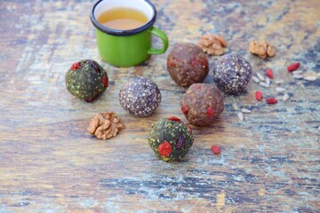 Homemade healthy raw vegan assorted energy balls with seeds, almond nuts, walnuts, goji berry, spirulina, coconut, cacao powder, acai berry and dates. Served with tea