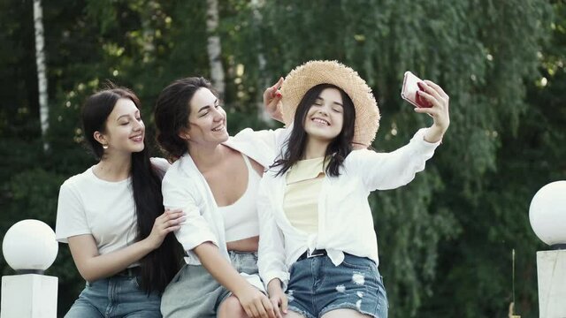 Friends party concept. Photo of happy European women taking selfie photo and laughing. The adies are having fun together outdoors.