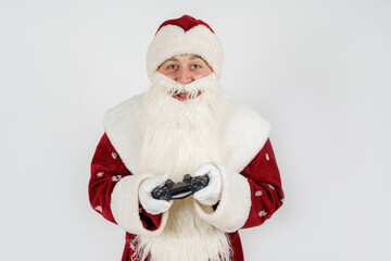 Santa Claus holds a joystick in his hands - he plays a computer game. Isolated on white