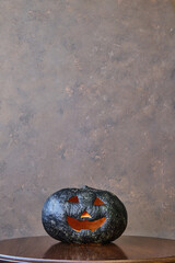black coloured pumpkin with glitter on wooden stool in front of a brown backdrop