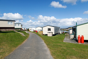 Fototapeta na wymiar Caravan Park - static caravans in Gower with a panoramic format and a blue sky background.