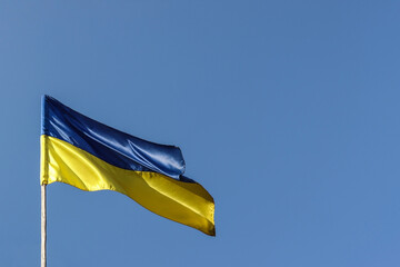 Ukrainian national flag flutters in the wind against the blue sky