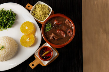traditional Brazilian dish called feijoada, contains rice, beens, beef, pork, orange, vegetables
