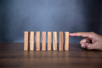Close-up fingers prevent the wooden block jenga game stick from falling domino concepts of...