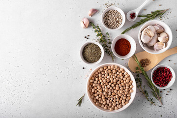 dried chickpeas in a white bowl with spices and herbs on a white table