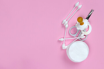 Ear sticks, cotton pads, scissors, baby hygiene products on a pink background. Copy space for text