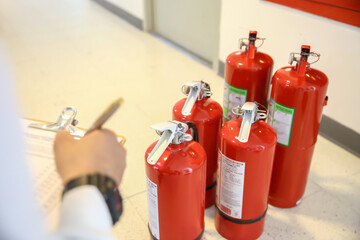 Fire fighter are checking the red fire extinguishers tank in the building concepts of fire...