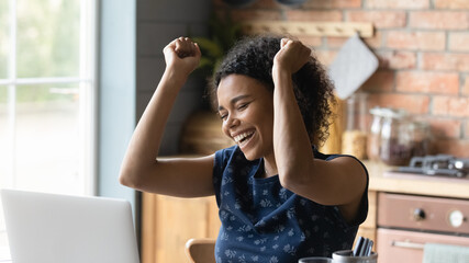 Overjoyed African American woman work on laptop feel euphoric winning lottery online. Happy excited...