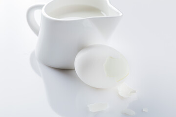 Fototapeta na wymiar broken boiled egg and milk jug on white