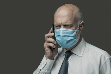 Businessman wearing a face mask and talking on the phone