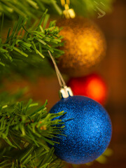 Blue Christmas ball on the tree. Blurred background. Portrait orientation photography.