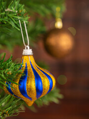Striped Christmas ball with sparkles on the Christmas tree. Blurred background of garlands.Portrait orientation of the photo.