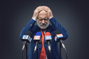 Sad politician with head in hands at the media briefing