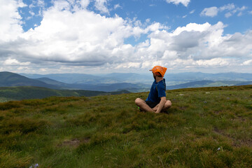 Guy looks at the beautiful mountains, sitting in the meadow.