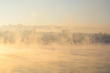 Winter landscape of fogy river in city. Seasons, climate change, ecology, environment. Extremely cold winter