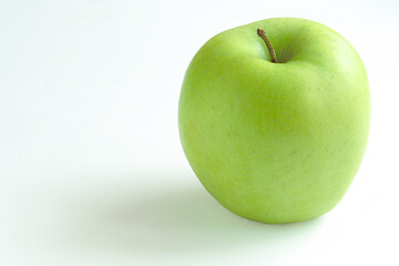 Ripe green apple on a white background, illuminated by daylight, close-up.