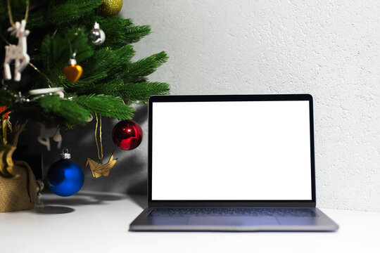 Close-up of laptop with mockup near Christmas tree.
