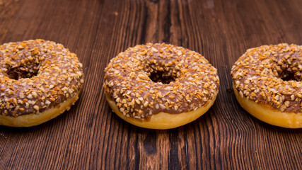 Glazed chocolate-coated doughnuts with sprinkles on a wooden Board,space for text