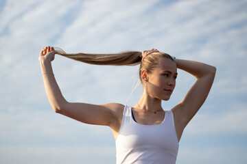 young fitness portrait of woman tying ponytale 