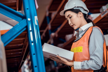 Confident Asian woman owner standing at goods warehouse store and check for control loading containers box from Cargo freight ship for import and export	