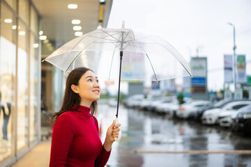 Asian woman in red sweater standing beside the road while raining 