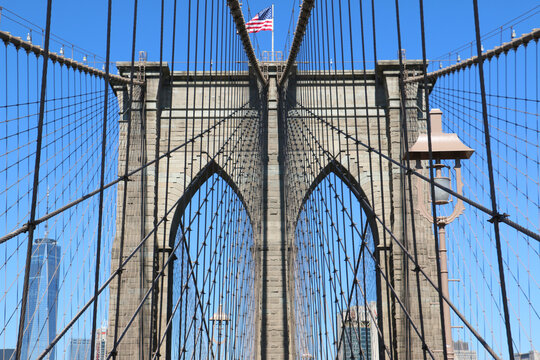 Brooklyn Bridge in New York City close up, One World Trade Center visible. American US Flag and blue sky