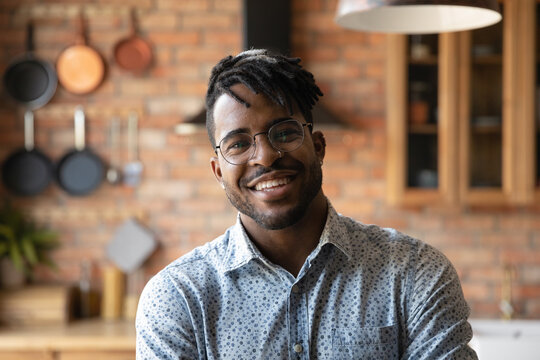 Close up profile picture of smiling African American man talk on video call have webcam conference online at home. Headshot portrait of happy 20s biracial male in glasses show confidence optimism.
