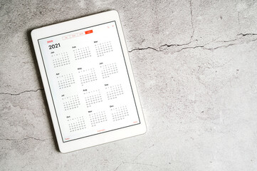 a tablet with an open calendar for 2021 year on a gray concrete background. space for text
