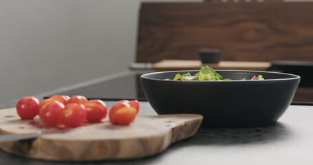 Closeup man making salad with greens , tomatoes and steak in a black bowl
