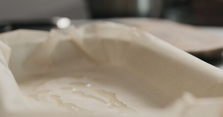 closeup pour oil into container with baking paper