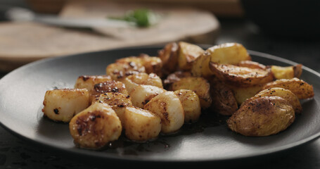 put baked potato wedges to roasted scallops on black plate