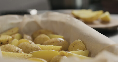 seasoning boiled potatoes with oil in a container with baking paper