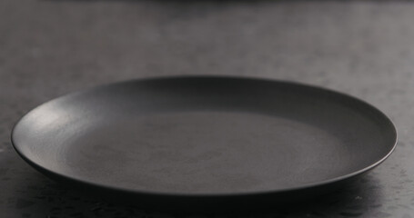 Empty black plate on concrete background