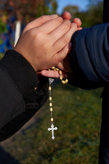 Mother and little son hold each other's hand with a rosary.