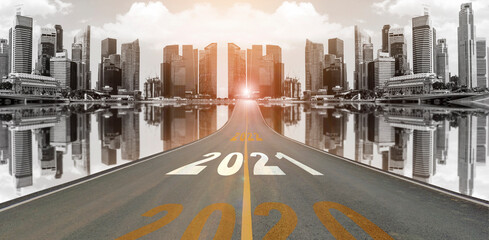 The number 2021 symbol represents the new year on the road heading to the city with beautiful skyscrapers background, New Year's and business target concepts.