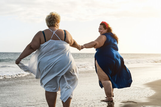 Happy plus size women having fun on the beach during vacation in tropical destination - Over size confident people lifestyle concept