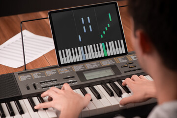 Man learning to play piano with help of an app on his tablet © yuriygolub