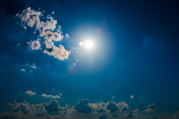 Fototapeta na wymiar Sun and clouds in the dark blue sky (backlight)